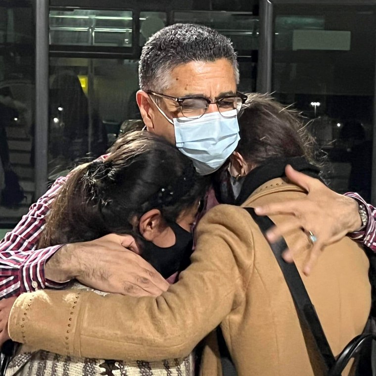 Ahmad Sarmast hugs Zohra and Farida, both aged 13, as they arrived in Doha, Qatar.
