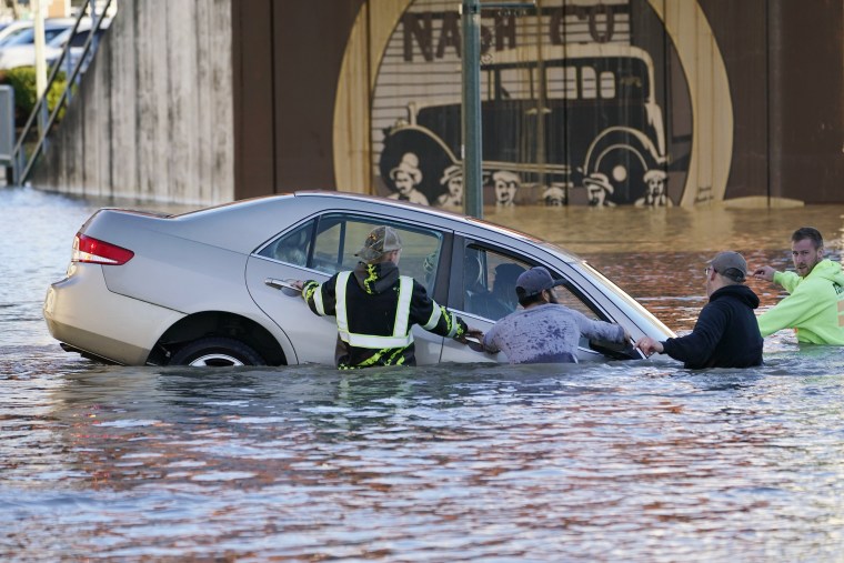 Image: Passersby surround a car whose driver went past a barricade and into the flooded Nooksack River on Nov. 16, 2021, in Ferndale, Wash.