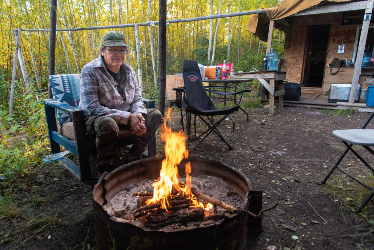 Jean L'Hommecourt warms at the fire outside the cabin she has built near the Fort McKay First Nation's village, about an hour's drive north of Fort McMurray in Alberta.