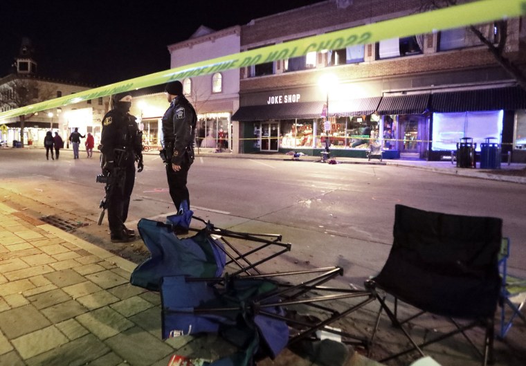 Image: Police stand near toppled chairs lining W. Main St. in downtown Waukesha, Wis., after an SUV drove into a parade of Christmas marchers