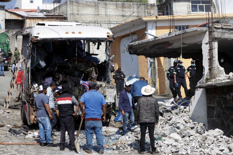 Government personnel work at a scene where at least 19 people were killed and 20 more injured after a passenger bus traveling on a highway crashed into a house in San Jose El Guarda, Mexico, on Nov. 26, 2021.