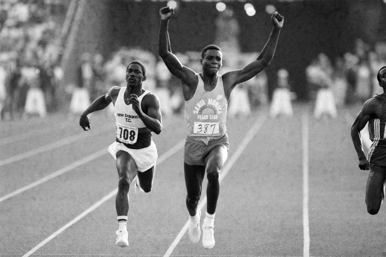 Image: Carl Lewis raises his arms in victory as he wins the 100-meter final ahead of third-place Emmit King,