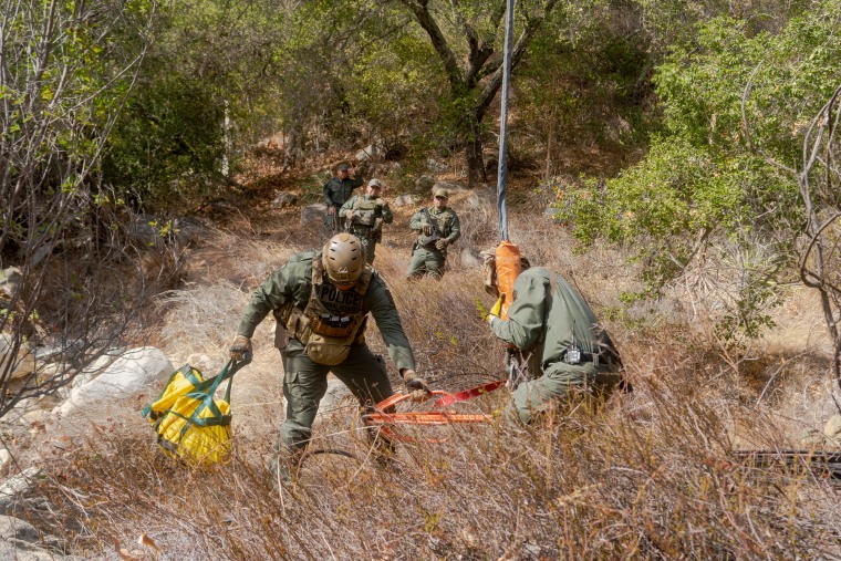 Image: Federal officers attach illegal grow site water tubing to a helicopter cargo hook.