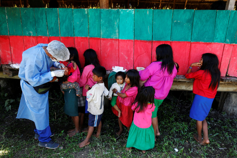 El médico Neuson Juran Apaza examina a una niña durante su visita a una comunidad aislada de la Amazonia peruana, donde un grupo de sanitarias llegó para vacunar a sus habitantes contra el COVID-19.