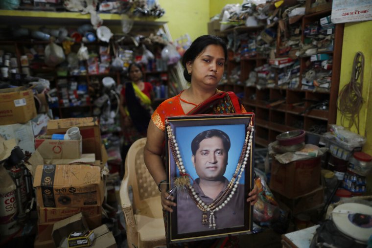 Reena Kesarwani sostiene una foto de su esposo, Anand Babu Kesarwani, quien murió de COVID-19 en su ferretería en India