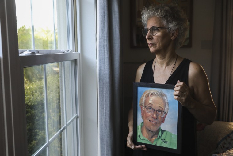 Cindy Johnson sostiene una pintura de su esposo, Steven, un farmacéutico jubilado que sobrevivió al cáncer de colon pero en diciembre de 2020 murió de coronavirus.