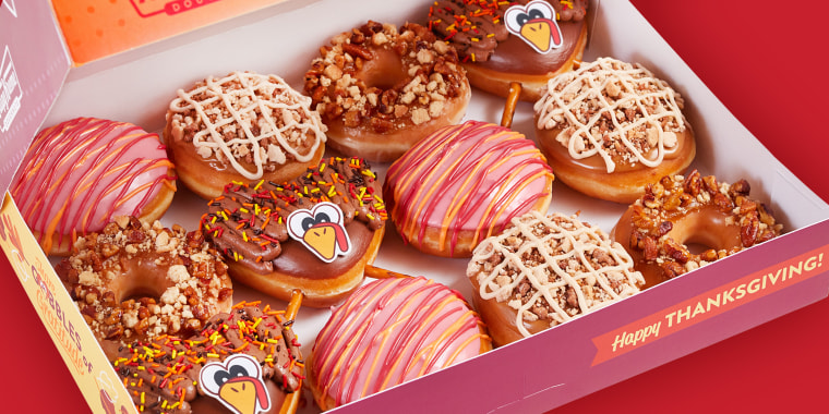 A dozen fall-themed donuts in a takeout box