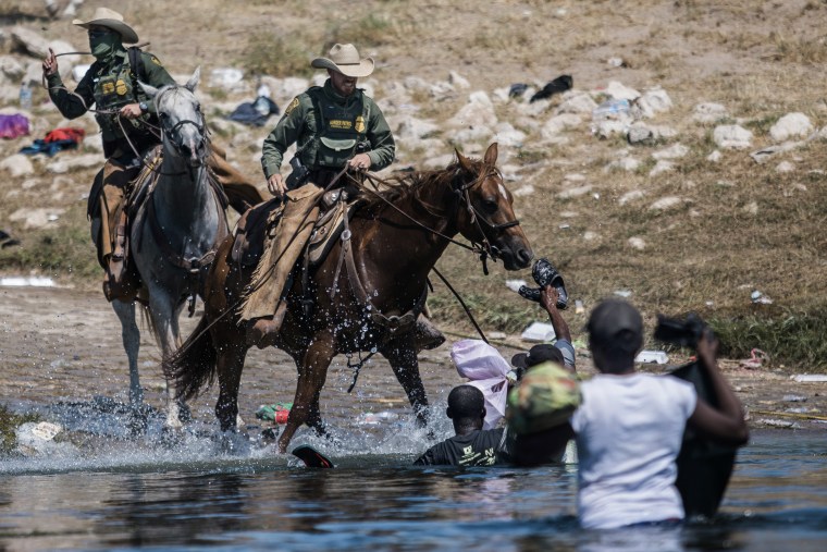 Agentes de la Patrulla Fronteriza de Estados Unidos montados intentan contener a los migrantes mientras cruzan el Río Grande desde Ciudad Acuña, México, hacia Del Río, Texas, el 19 de septiembre de 2021.
