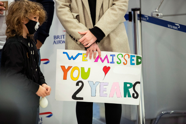 Una familia espera a sus seres queridos tras el aterrizaje del vuelo de British Airways en el aeropuerto internacional JFK de Nueva York. “Te extrañamos. Dos años”, dice el cartel.