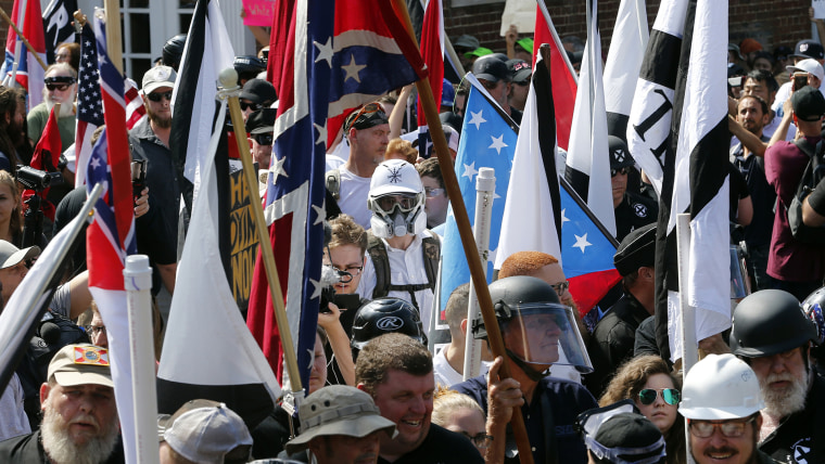 Manifestantes nacionalistas blancos caminan hacia la entrada del Parque Lee rodeados de contramanifestantes en Charlottesville, Virginia, el sábado 12 de agosto de 2017