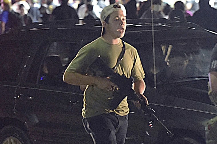 Kyle Rittenhouse carries a weapon as he walks along Sheridan Road in Kenosha, Wis., on Aug. 25, 2020.