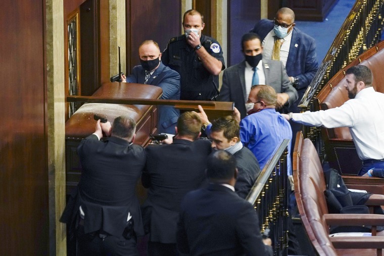Image: Capitol Police with guns drawn stand near a barricaded door as protesters try to break into the House Chamber on Jan. 6, 2021.