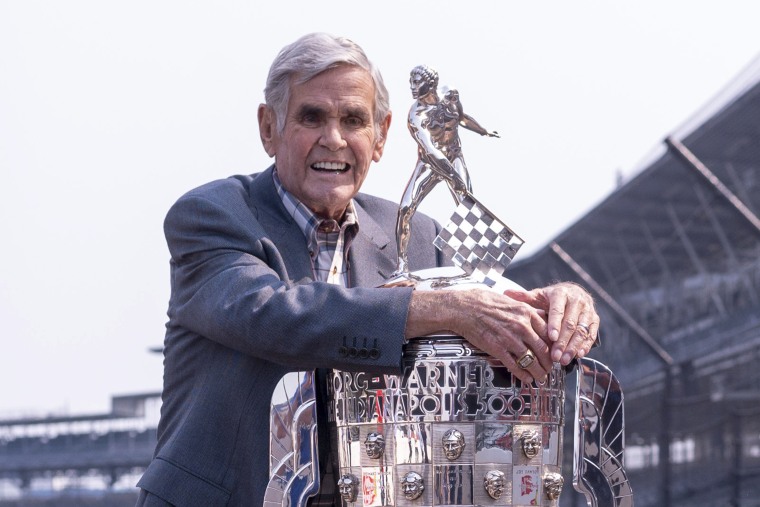 Al Unser hugs the Borg-Warner Trophy at the Indianapolis Motor Speedway on July 20, 2021.