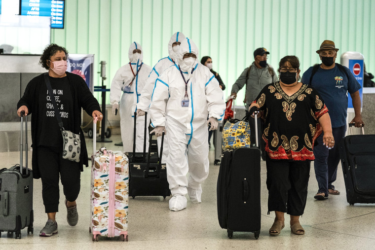 Image: Air China flight crew members in hazmat suits walk through the arrivals area at Los Angeles International Airport in Los Angeles on Nov. 30, 2021.