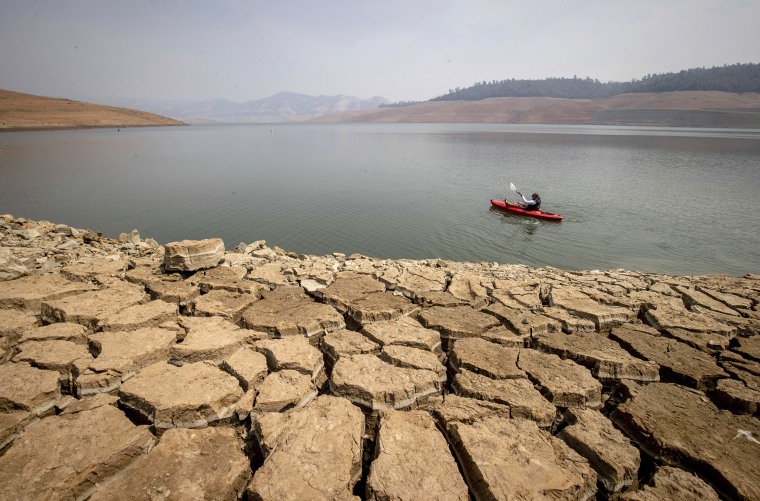 A kayaker fishes in Lake Oroville on Aug. 22 as water levels remain low because of continuing drought conditions in Oroville, Calif.
