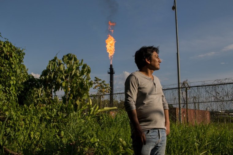 Javier Solís, abogado de la comunidad de El Edén, posa para un retrato frente al mechero de una planta procesadora de petróleo.