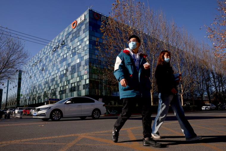 Image: People walk past the headquarters of the Chinese ride-hailing service Didi in Beijing