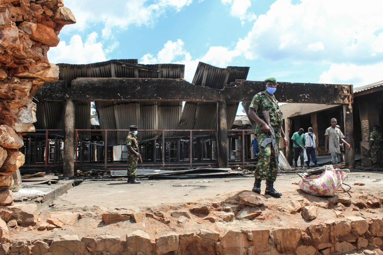Security officers stand next to the burned prison in Gitega, Bujumbra, Burundi, on Dec. 7, 2021.