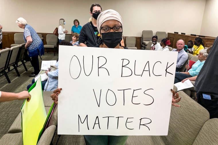 Image: Yoshunda Jones, a local activist who protested the elimination of Sunday voting, holds up a sign in Spalding County