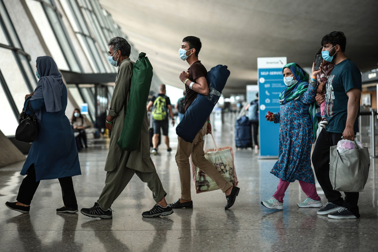 Refugees walk through the departure terminal to a bus at Dulles International Airport after being evacuated from Kabul following the Taliban takeover of Afghanistan on Aug. 31, 2021 in Dulles, Va.
