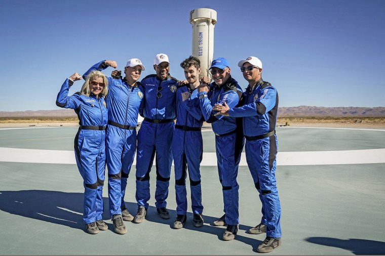 Image: Blue Origin's latest space passengers from left, Laura Shepard Churchley, Dylan Taylor, Michael Strahan, Cameron Bess, Lane Bess, and Evan Dick pose for a photo in front of the booster rocket at the spaceport near Van Horn, Texas, on Dec. 11, 2021.