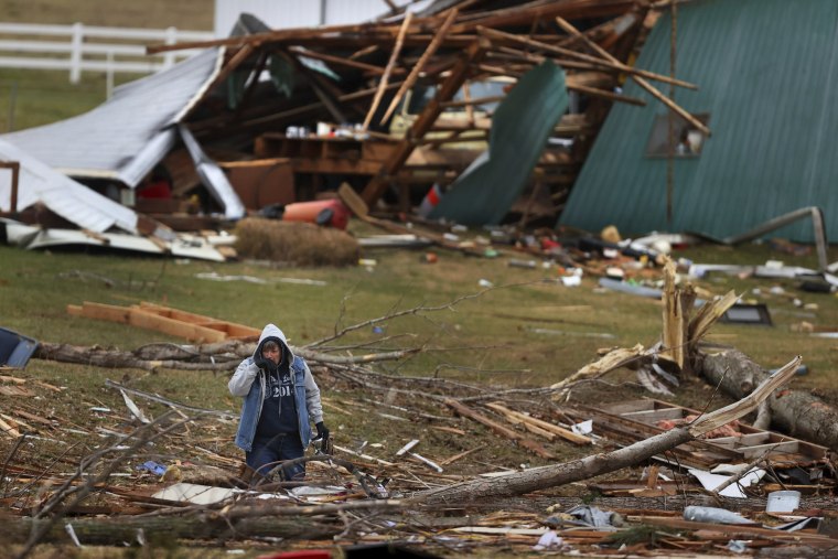 Image: A woman searches for valuables amidst the remnants of a home on Dec. 11, 2021 on Highway F in Defiance, Mo.
