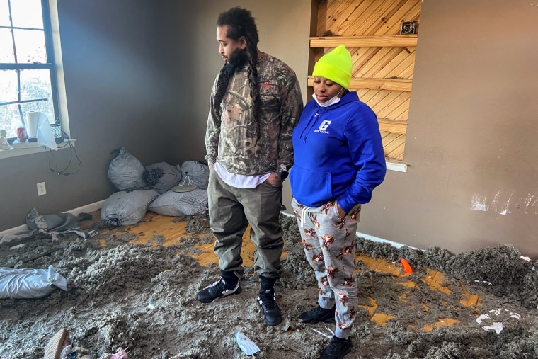 Mark and Courtney Saxton look at their home which was devastated during a tornado in Mayfield, Ky., on Dec. 12, 2021. Mark Saxton is a survivor of the Candle factory.