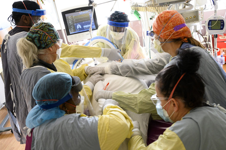 Image: Respiratory therapist Spirya Andrews, back center, works with a team of critical care nurses and assistants to supine a critically-ill Covid patient in the South Seven Intensive Care Unit Wednesday, Dec. 8, 2021 at North Memorial Health Hospital in Robbinsdale, Minn.