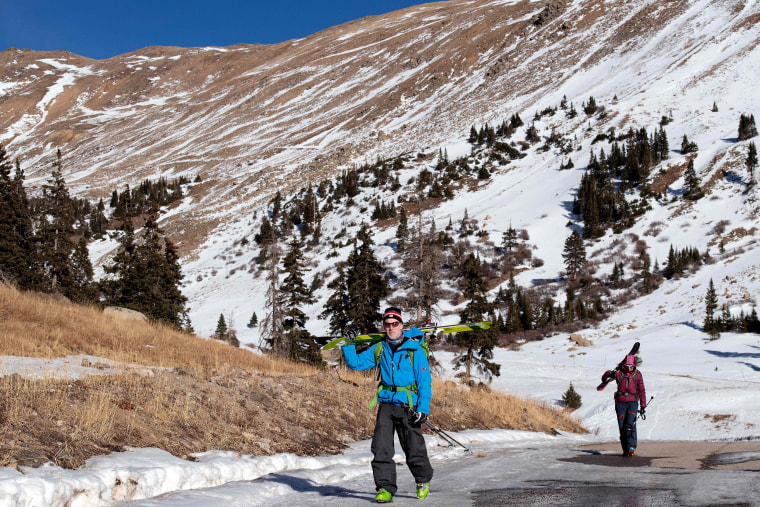 Image: Glenn Cain and Mary Taylor walk on exposed pavement after backcountry skiing in Summit County, Colo., on Dec. 3, 2021.