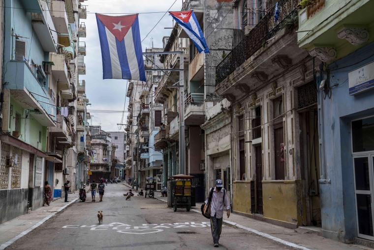 A man walks under Cuban flags flying over a street in Havana on July 26.