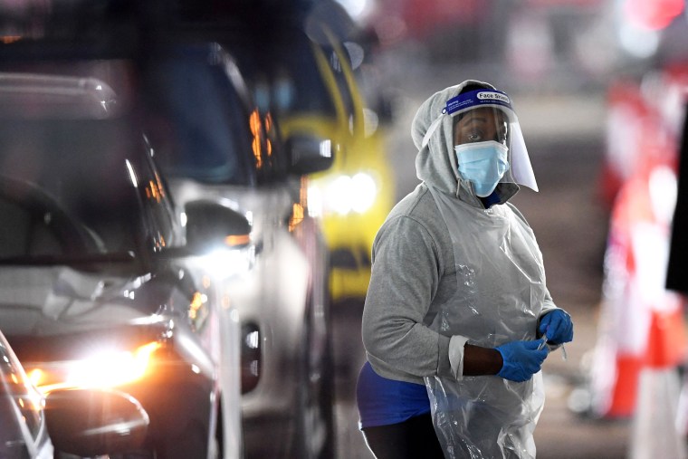 A medical worker returns to a hut after dealing with a member of the public in their car at a drive-in coronavirus testing center in London on Dec. 18, 2021.
