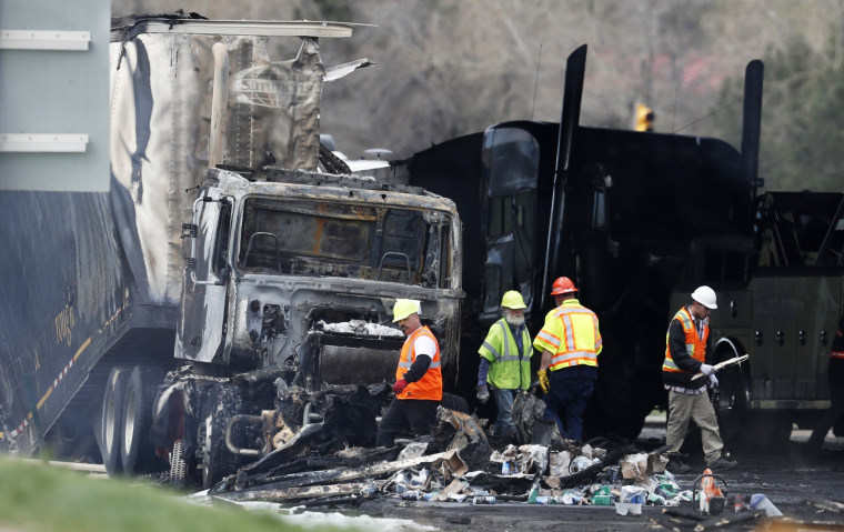 Workers clear debris from the eastbound lanes of Interstate 70 on April 26, 2019, in Lakewood, Colo., after a deadly pileup involving a semi-truck hauling lumber.