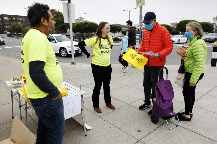 Siva Raj and his partner, Autumn Looijen, hand out shopping bags with San Francisco School Board recall information on them.
