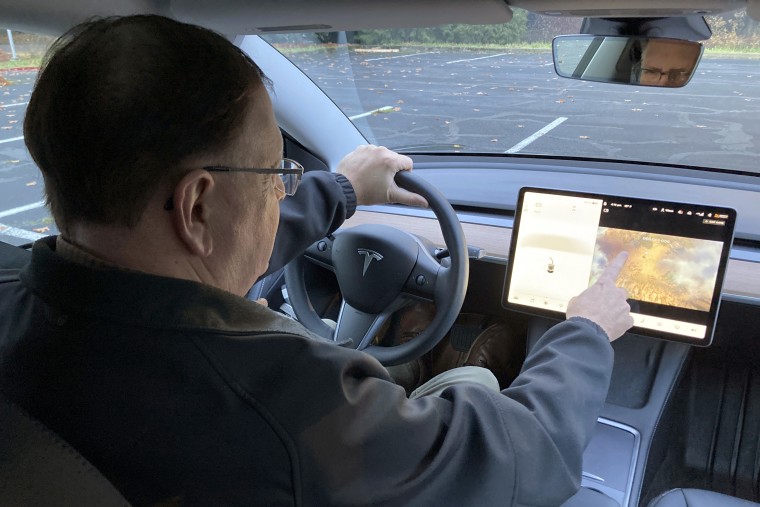 Vince Patton, a new Tesla owner, demonstrates on a closed course in Portland, Ore., how games can be played on the vehicle's console on Dec. 8, 2021.