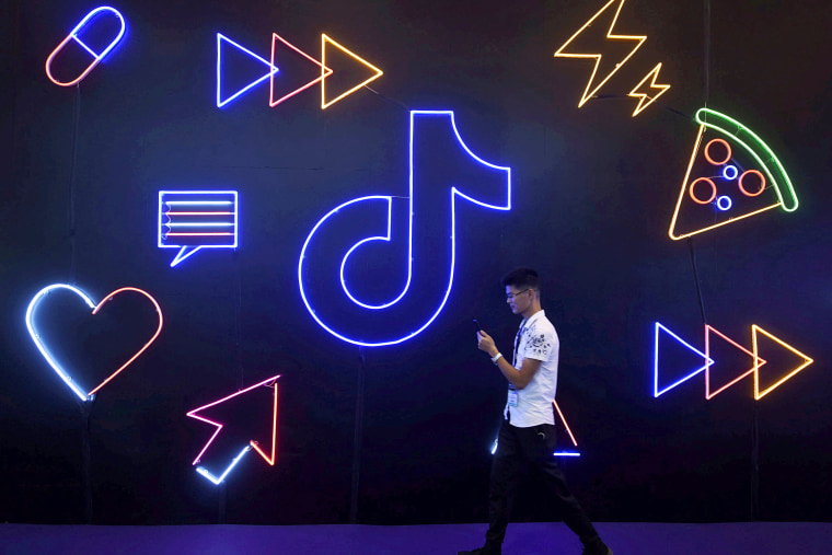 Image: A man holding a phone walks past the TikTok, logo at the International Artificial Products Expo in Hangzhou, China on Oct. 18, 2019.
