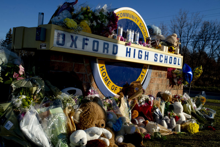 Familiares, amigos y estudiantes colocan arreglos florales, velas y mensajes en un memorial cerca de la entrada de la escuela secundaria de Oxford, Michigan.