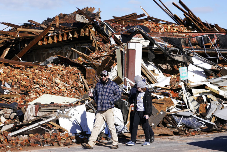 Residentes de Mayfield, Kentucky, caminan junto a los escombros causados por tornados el sábado 11 de diciembre de 2021.