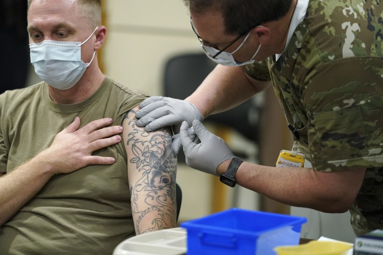 El sargento Travis Snyder, a la izquierda, recibe la primera dosis de la vacuna contra el COVID-19 de Pfizer administrada en el Centro Médico del Ejército Madigan en la Base Conjunta Lewis-McChord en el estado de Washington, el 16 de diciembre de 2020.