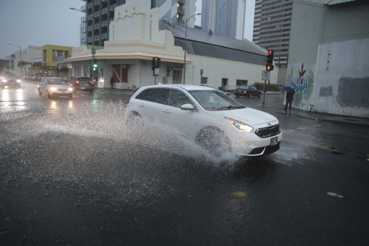 Un coche gira hacia la calle inundada de Cooke en Honolulu, Hawái, el lunes 6 de diciembre de 2021.