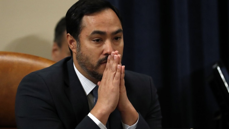 Un hombre latino con barba sostiene las dos manos frente a su boca en atención; es el representante por Texas Joaquin Castro durante una sesión legislativa.