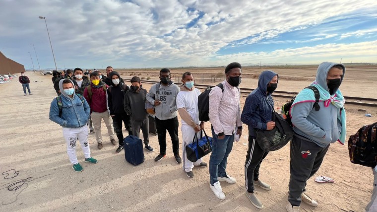 Un grupo de migrantes espera cerca de Yuma, Arizona, a subir a uno de los autobuses de la Patrulla Fronteriza para ser procesados tras cruzar la frontera ilegalmente, el 7 de diciembre de 2021.