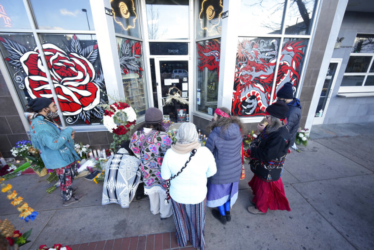 Un grupo de personas deposita flores y velas frente a uno de los locales de tatuajes que forman parte de la ruta que siguió Lyndon James McLeod en la ola de tiroteos que perpetró el 27 de diciembre en Denver, Colorado.