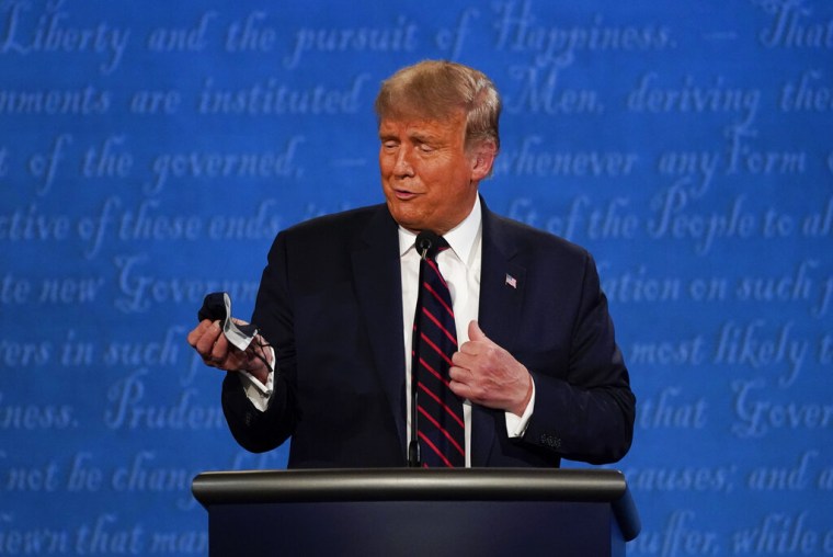Donald Trump mira la mascarilla que sujeta en una de sus manos durante el debate presidencial que mantuvo con el entonces candidato demócrata, Joe Biden, el 29 de septiembre de 2020 en Cleveland, Ohio.