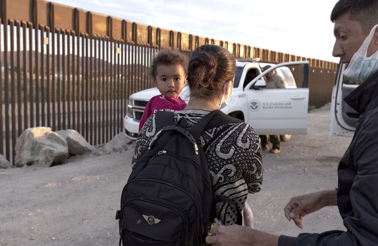 En esta fotografía de archivo del 10 de junio de 2021, una familia migrante de Brasil espera ser procesada por agentes de la Patrulla Fronteriza después de atravesar una brecha en el muro fronterizo con México en Yuma, Arizona.
