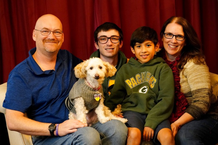 De izquierda a derecha, Michael Olson, Paul Olson, de 18 años, Porter Olson, de 10, y Nicole Olson con su perro llamado Dotty en su casa, el jueves 17 de diciembre de 2021, en Phoenix. Porter fue cedido al nacer a través de lo que se conoce como ley de refugio seguro.