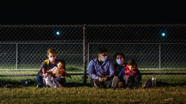 Familias migrantes se sientan juntas mientras esperan subir a un autobús de la patrulla fronteriza después de cruzar el Río Grande hacia Estados Unidos en La Joya, Texas.