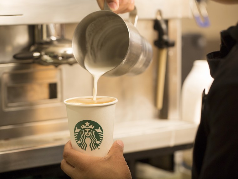 Starbucks barista pours milk into a cup
