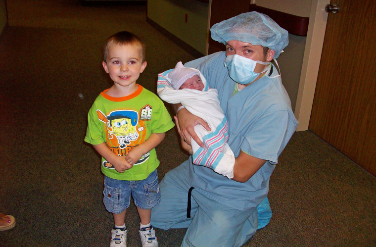 Vanner Johnson hold his newborn son, Tim, as his brother, Vanner, looks on.