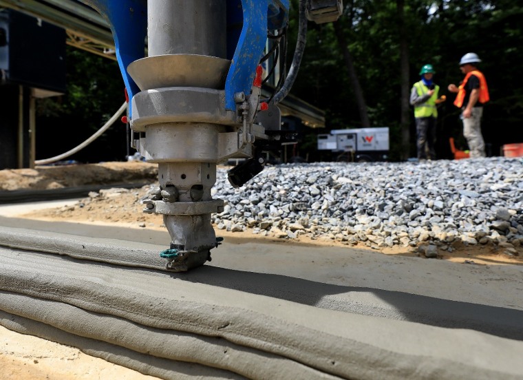 The printer head of a giant 3D printer begins laying cement for the foundation of a Habitat for Humanity home.