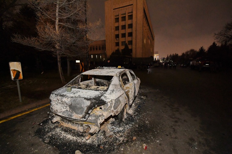 Image: A burned car is seen near the mayor's office in Almaty